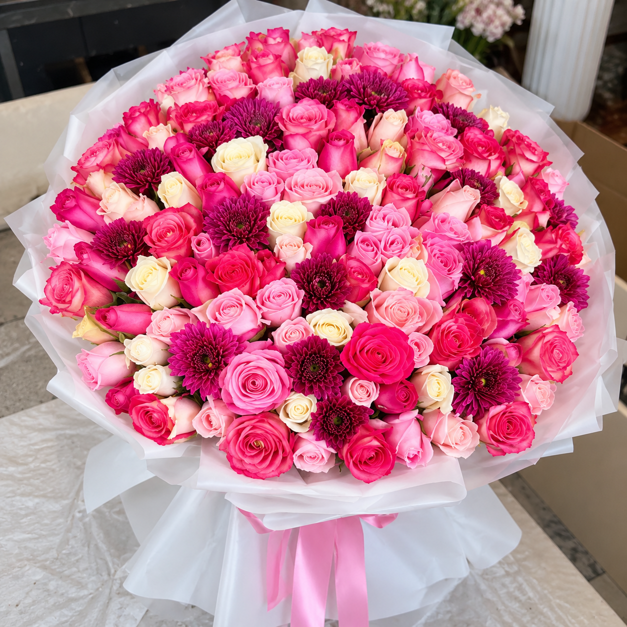 Nuage de Rose – Bouquet de roses naturelles – PrimaRosa Grand bouquet de roses roses et blanches avec fleurs mauves, emballage blanc et ruban rose, photographié sur fond clair – PrimaRosa.